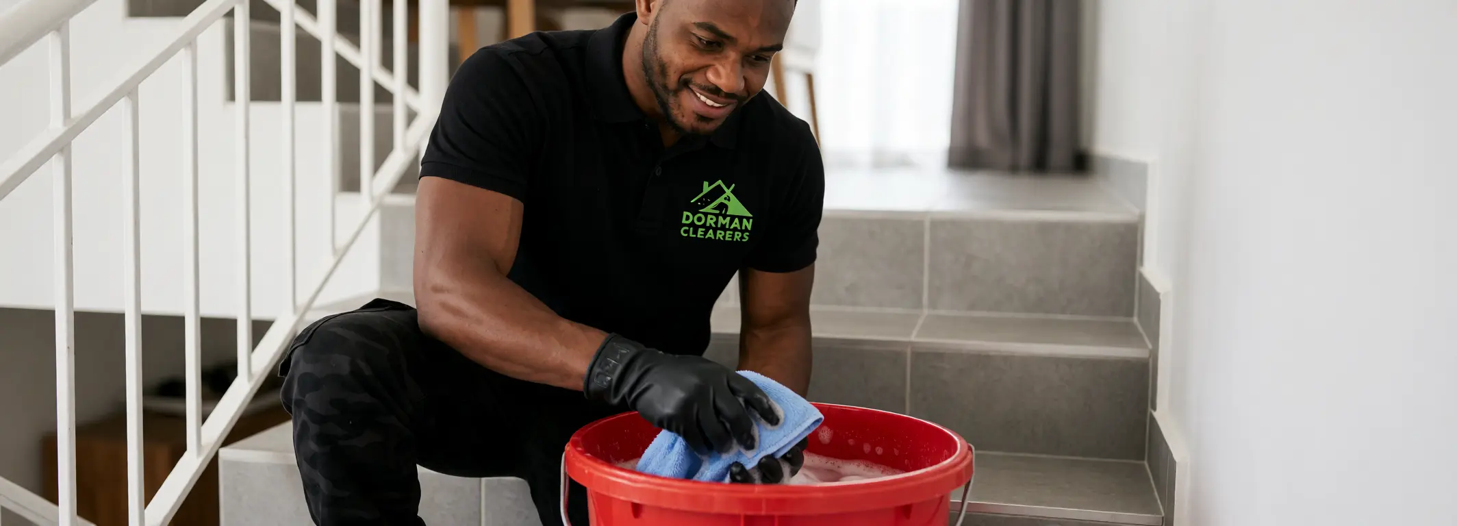 Cleaner wringing a cloth into a bucket on stairs